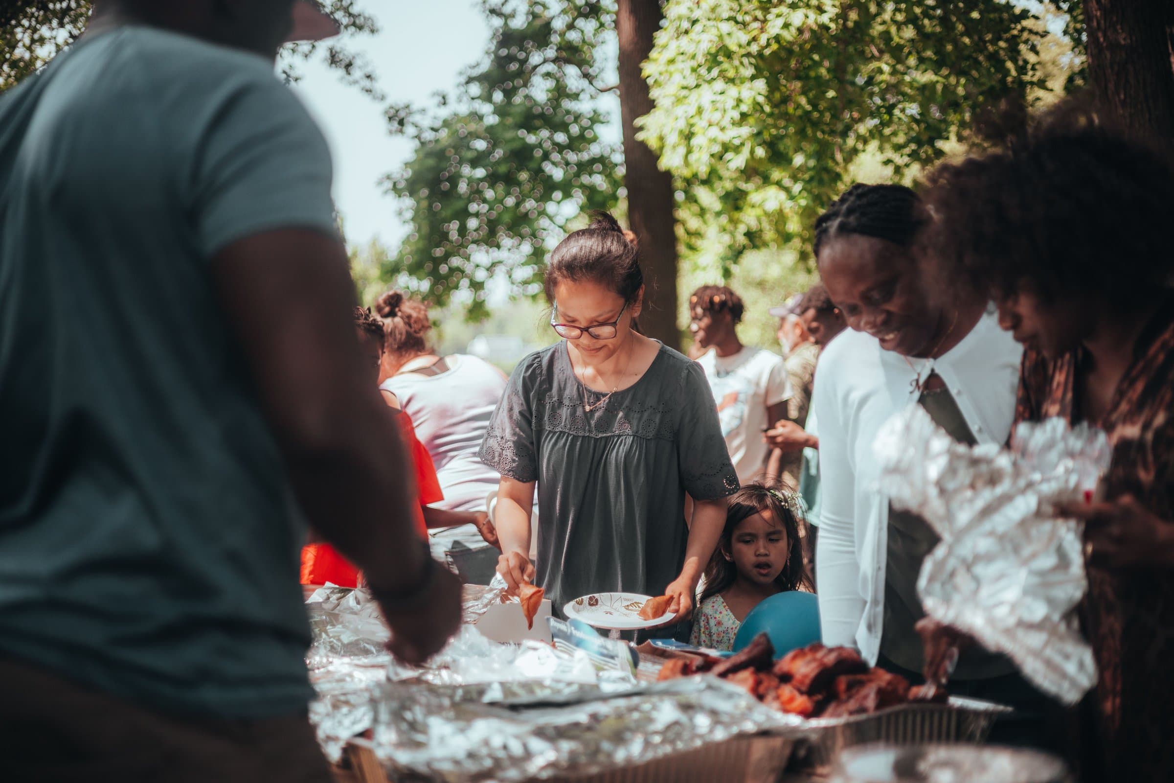 Neighbours and families gathered together sharing a meal outdoors