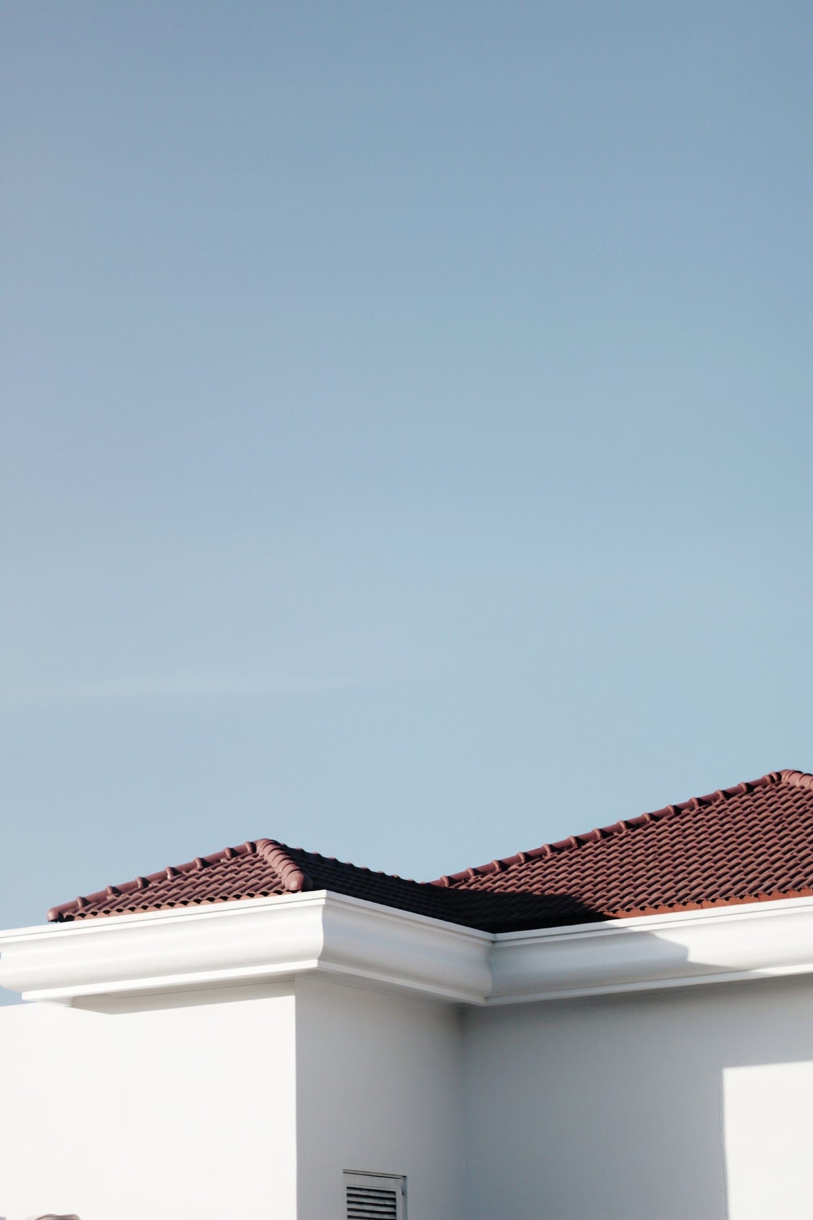 A minimalist view of a tiled roofline against a clear blue sky